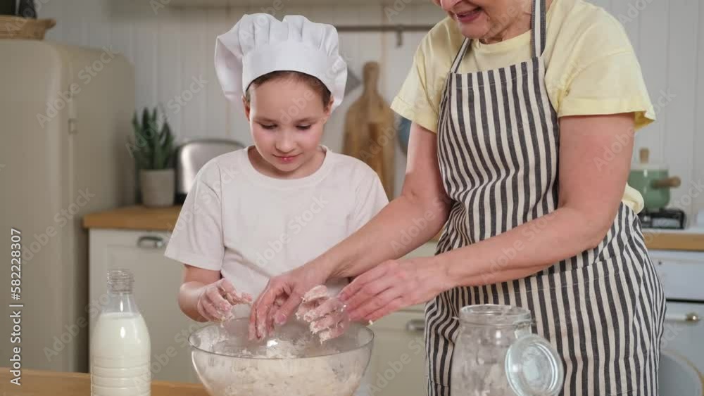 Happy family in kitchen. Grandmother and granddaughter child cook in kitchen together. Grandma teaching kid girl knead dough bake cookies. Household teamwork helping family generations concept Happy family in kitchen. Grandmother and granddaughter child cook in kitchen together. Grandma teaching kid girl knead dough bake cookies. Household teamwork helping family generations concept