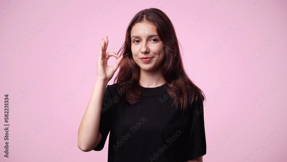 4k video of cute girl showing OK sign on pink background. 4k video of cute girl showing OK sign on pink background.