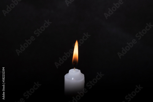 white burning candle on a black background 
