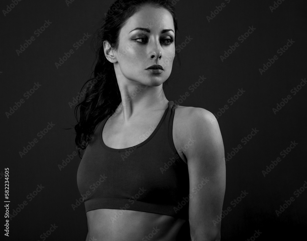 Confident sportswoman in sportsbra , holding hands on waist, fitness trainer standing in power pose, workout in gym isolated on black background Confident sportswoman in sportsbra , holding hands on waist, fitness trainer standing in power pose, workout in gym isolated on black background
