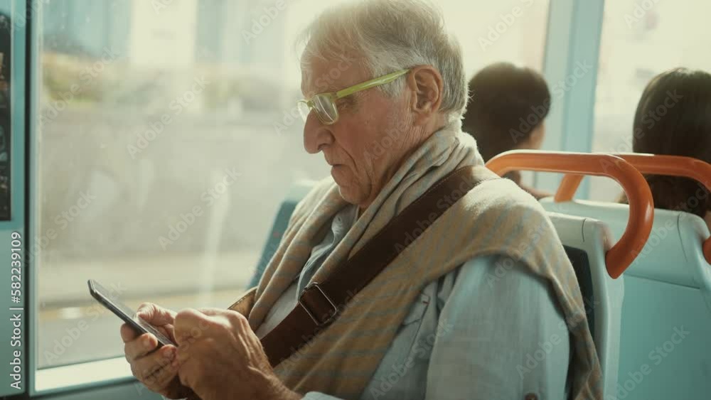 Senior man using mobile smartphone while traveling by public bus