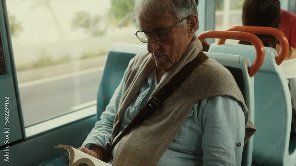 Senior man reading book while traveling with bus