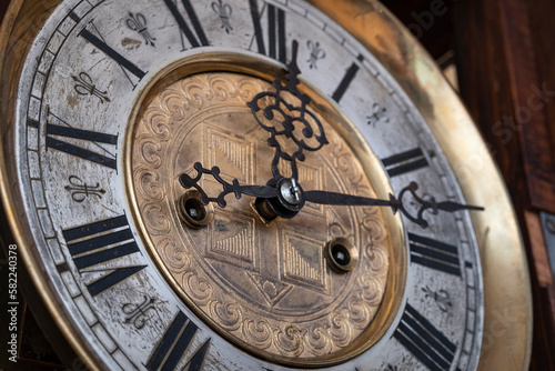 Old wooden clock with a pendulum hanging on the wall