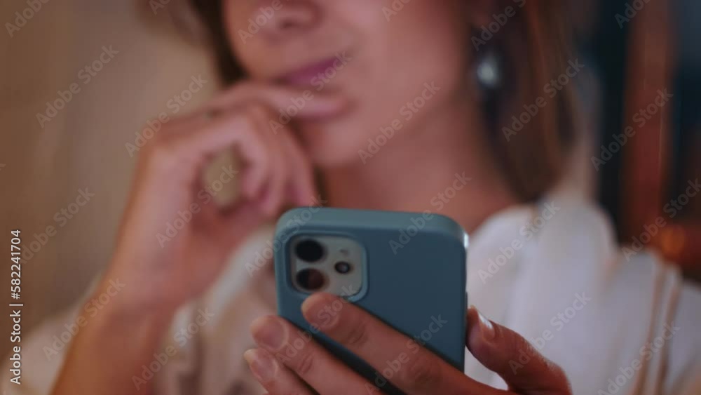 Close-up face of young beautiful Caucasian woman using phone mobile app in blue case thinking, touching lips.