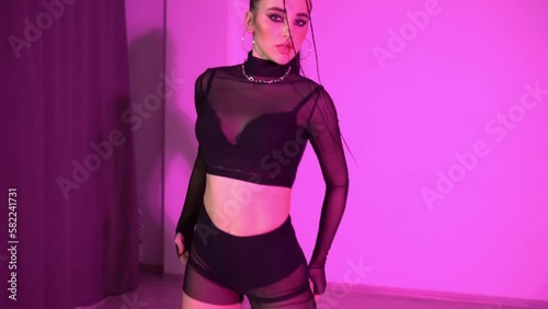 Sexy girl in black top and transparent short leggings is dancing on the floor in red lighted room