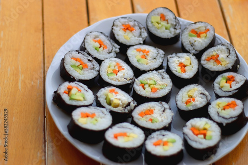 Plates with homemade sushi rolls on wooden table. Vegetarian cream cheese and vegetable sushi. Selective focus.