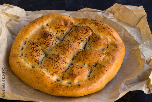 Traditional Turkish Ramadan Bread with oven baking paper on black surface 