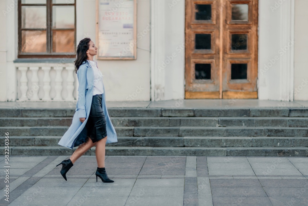 Woman walks in the city, lifestyle. Young beautiful woman in a loose light sweater, brown skirt and sneakers with a hat. Woman walks in the city, lifestyle. Young beautiful woman in a loose light sweater, brown skirt and sneakers with a hat.