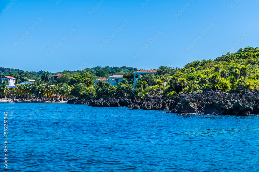 A view past the rocky shoreline of a bay adjacent to West Bay on Roatan Island on a sunny day