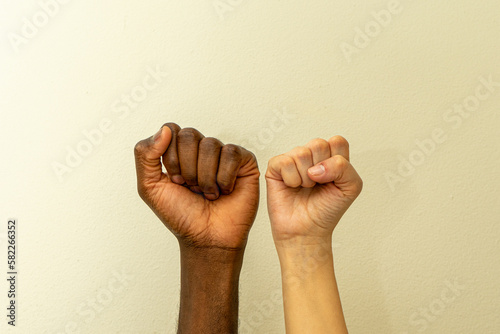 Two clenched white female and black male fists supporting each others
