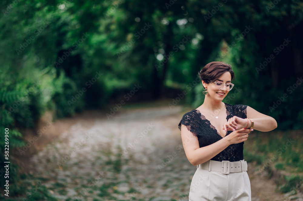 Stylish woman wearing beige pants and a black lace top walking in the nature Stylish woman wearing beige pants and a black lace top walking in the nature