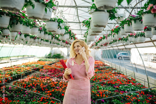 Young woman working in a greenhouse and using a smartphone photo