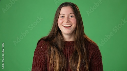 Portrait of young beautiful funny casual female. Teen girl talking to friends family online  blogging  laughing on green screen. Camera point of view