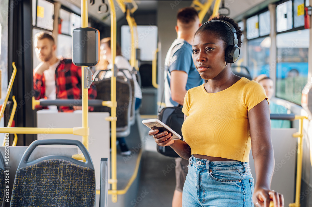 Obraz premium African american woman riding in a bus and using a smartphone