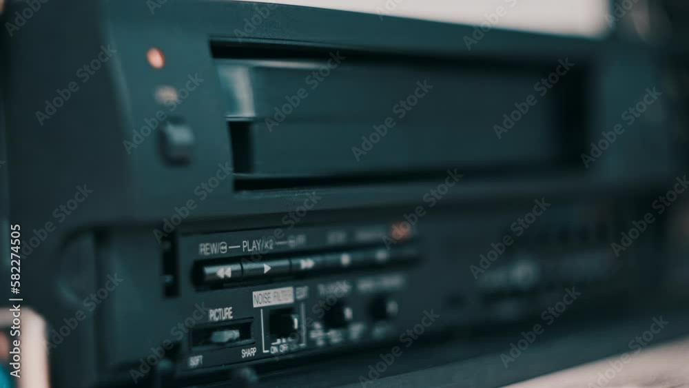 Eject VHS tape cassette from VCR player. Male hand pushes a button and