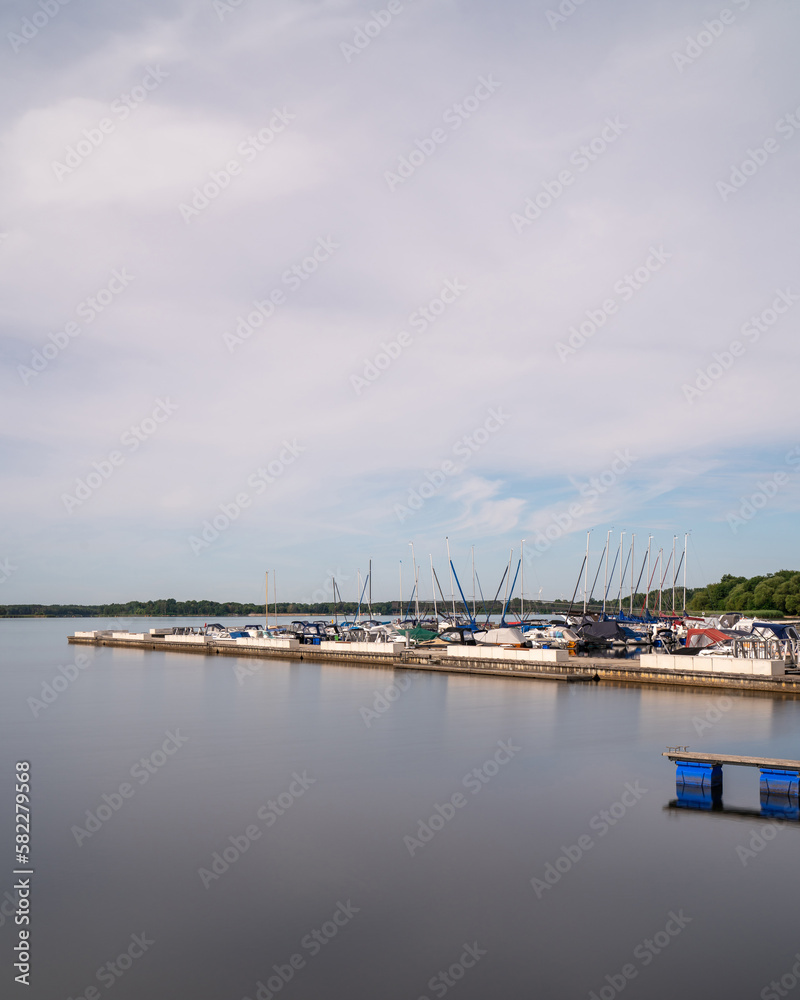 Fototapeta premium Pier on lake Senftenberg in Germany. Moored ships, boats and yachts. calm water
