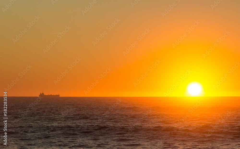 Sunsetting over the atlantic ocean seen from Porto, portugal. A large boat sits on the horizon.