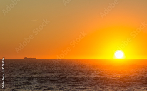 Sunsetting over the atlantic ocean seen from Porto  portugal. A large boat sits on the horizon.