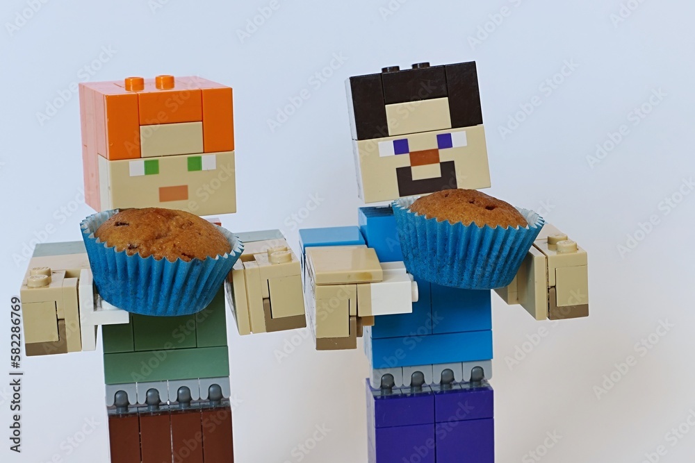 Fototapeta premium LEGO Minecraft figures of Steve and Alex holding small muffin cakes in blue paper muffin cups