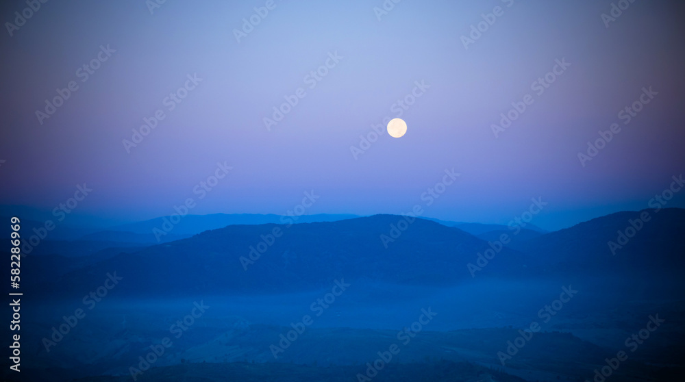 The moon, between the mountains on a summer night