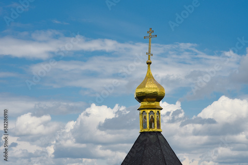 Golden ancient dome with a cross in the Lavra against the sky