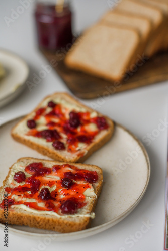 Bread with butter and cranberry jam is on the table and ready to eat. A delicious and sweet breakfast. Aesthetically pleasing serving of food. Recipe for toast with butter and jam.