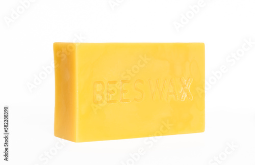 An angled view of a brick of pure beeswax on a white background