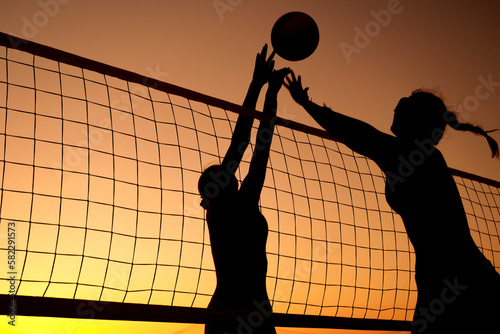 Silhouette women playing beach volleyball on sunset. photo