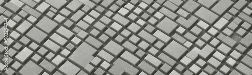 Geometric patterned patio floor made of grey and black mosaic stones with white and black brickwork walls as backdrop. Small and large fragmented pieces of cobblestone create tetris like effect.