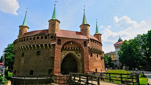 Krakow, Poland - Jun 09, 2018: front view of the exterior of Krakow Barbican on a sunny day with bright blue sky and clouds in the background photo