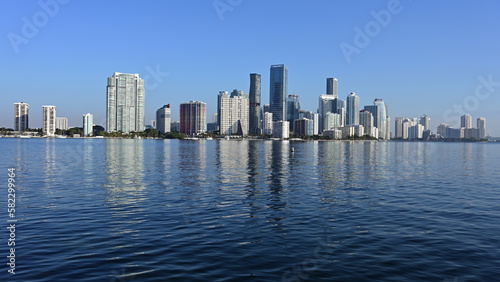 Miami, Florida skyline reflected on calm Biscayne Bay in morning light on sunny clear day. © Francisco