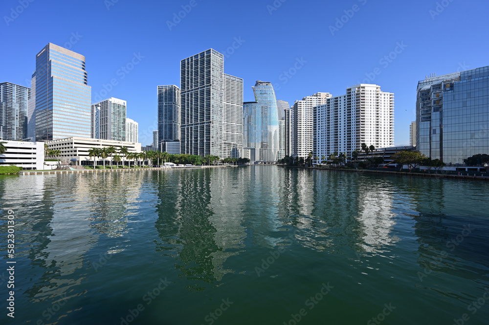 Residential and office towers in downtown Miami, Florida reflected in calm water of Biscayne Bay on sunny clear morning.