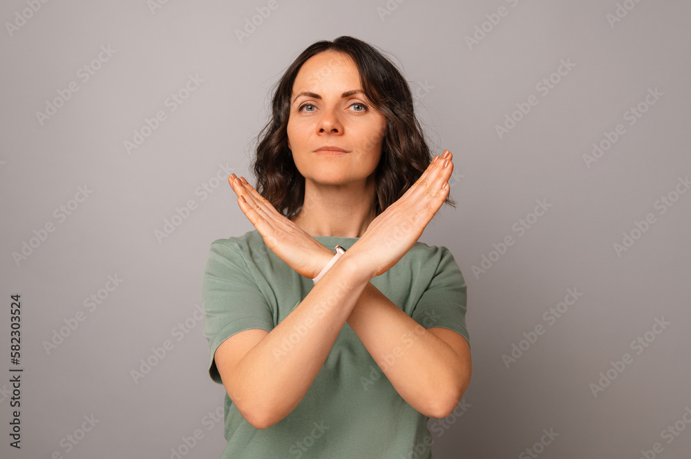 Obraz premium Studio shot of a confident mid age woman is crossing hands for a stop gesture.