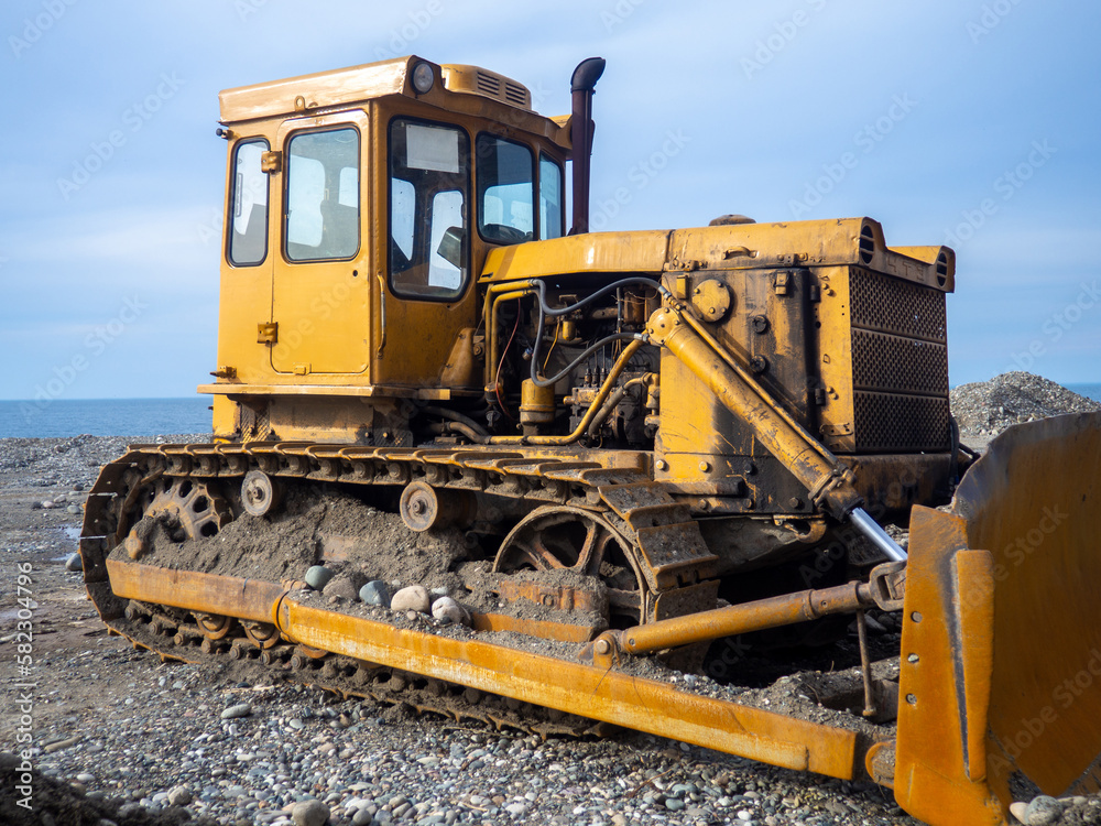 Bulldozer for excavation.  Tractor from the Chelyabinsk Tractor Plant. Part of an orange tractor. Soil of pebbles and earth