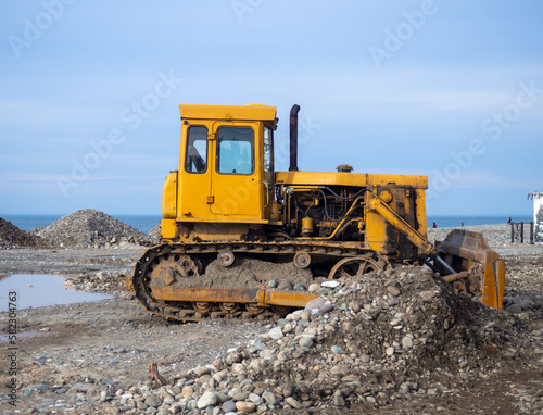 Bulldozer for excavation. Tractor from the Chelyabinsk Tractor Plant. Part of an orange tractor. Soil of pebbles and earth