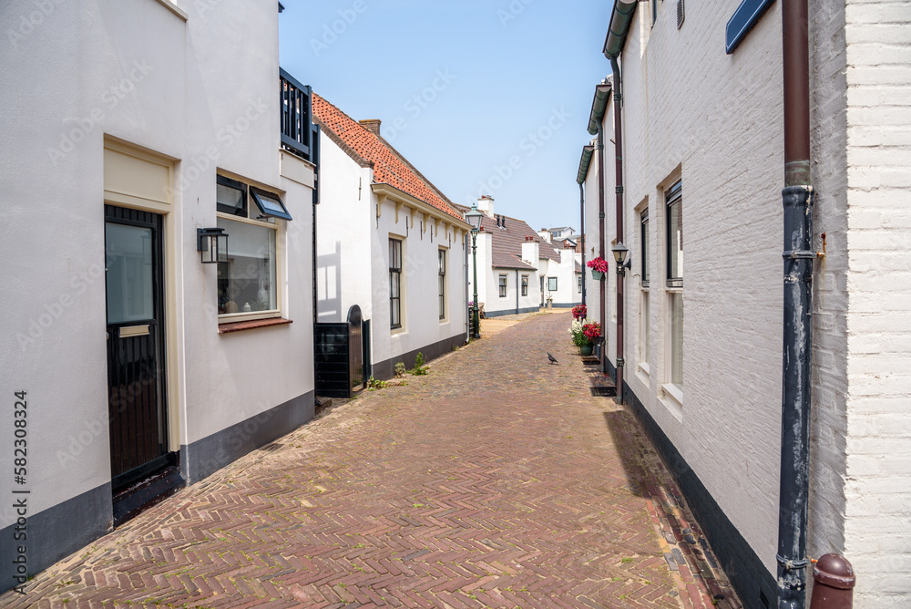 Narrow street lined with white holiday cottages in a seaside town in the Netherlands on a sunny summer day