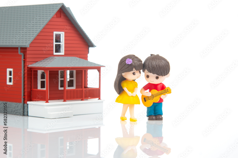 miniature people. romantic couple of young people near the house model on a white background. friendship and great relationship