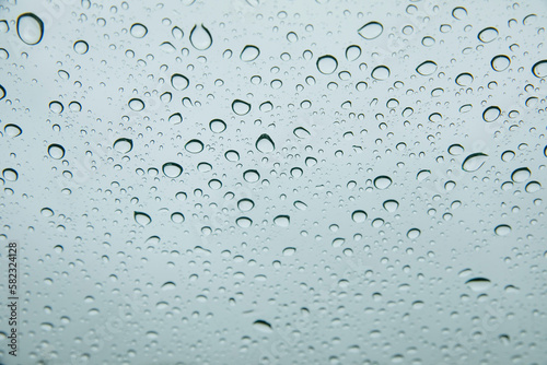 Round blue drops of water in the middle of a rain on a window