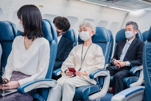 マスクをして飛行機に乗る乗客 © maroke