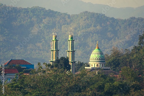 a mosque looks top surrounded by hills that are green and fresh