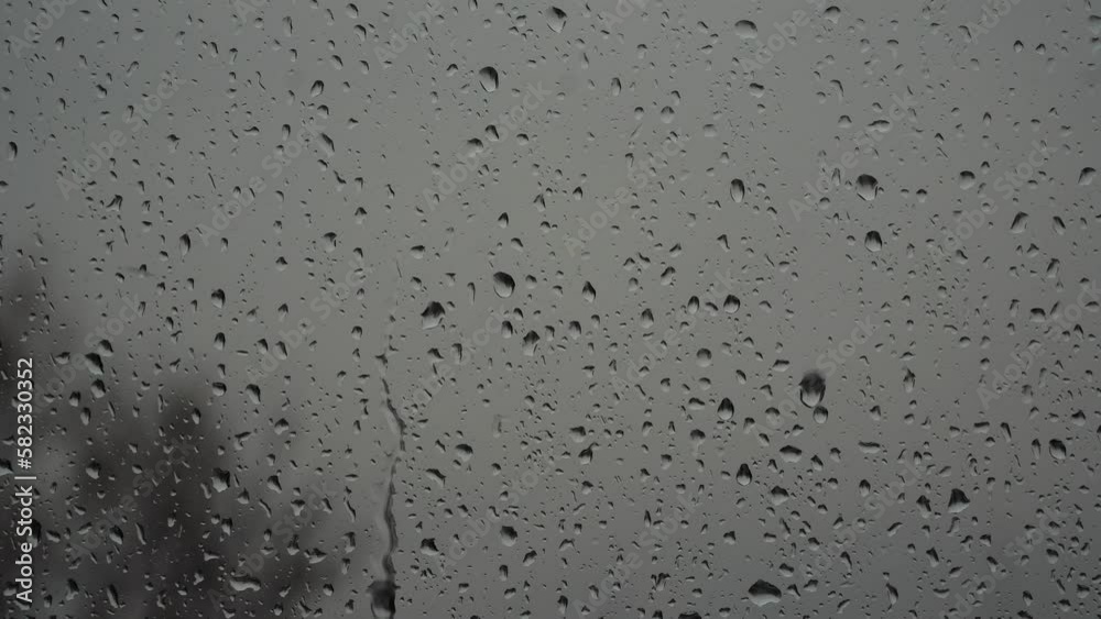 raindrops on window in moody sky. Close up view of water droplets on window flowing down on stormy sky. raindrops on window in moody sky. Close up view of water droplets on window flowing down on stormy sky.