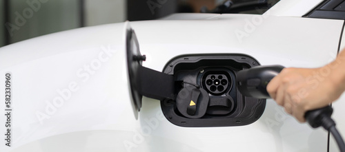 Progressive concept of hand insert an emission-free power connector to the battery of electric vehicle at home. Electric vehicle charging via cable from charging station to EV car battery