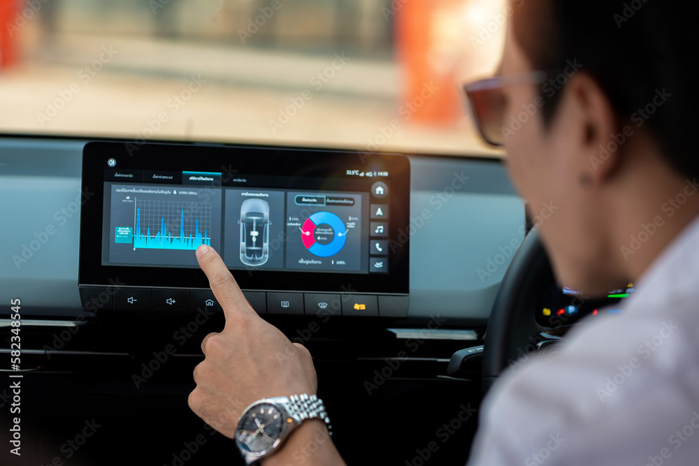 An electric car driver is viewing the vehicle's electricity consumption details through a touch screen. An electric car driver is viewing the vehicle's electricity consumption details through a touch screen.