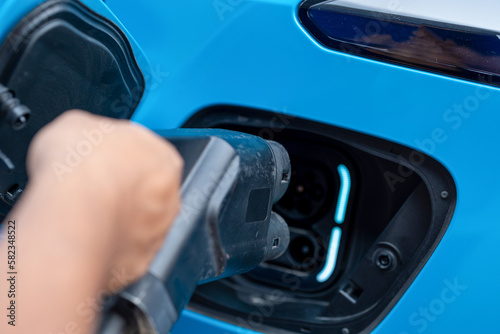 The driver of the electric car inserts the electrical connector to charge the batteries. © ND STOCK