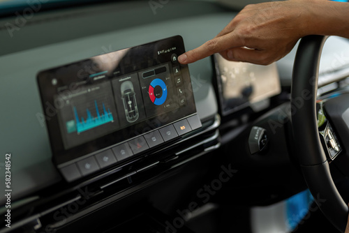 An electric car driver is viewing the vehicle's electricity consumption details through a touch screen.