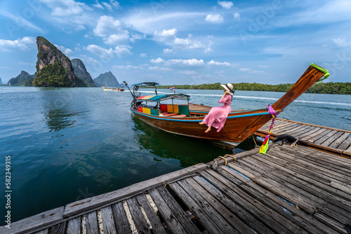 A pink-dressed girl sits on a long-tailed boat to admire the beauty of the Thai sea of ​​Koh Panyee. © munduuk