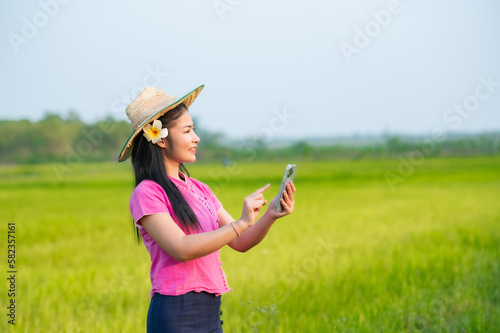 Beautiful asian woman working laptop outdoors in rice fields.