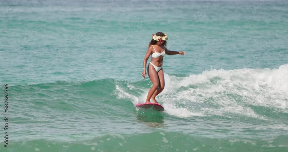 Young African-American woman surfing on the longboard in Hawaii in the ocean Young African-American woman surfing on the longboard in Hawaii in the ocean
