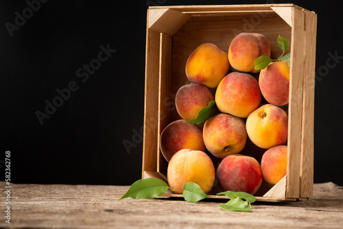 Peaches in a box on a wooden background.