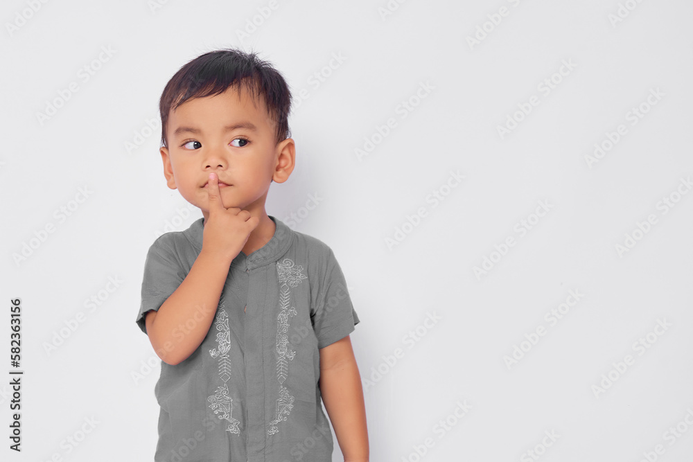 toddler Asian muslim boy showing silence gesture isolated on white studio background toddler Asian muslim boy showing silence gesture isolated on white studio background